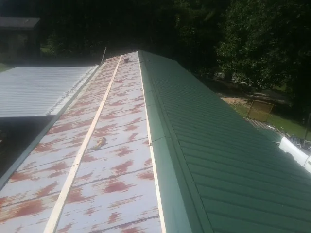 Old rusted panels beside newly installed green metal roofing — Wind Damage Roof Repair by Roofing Brothers in Valley Center