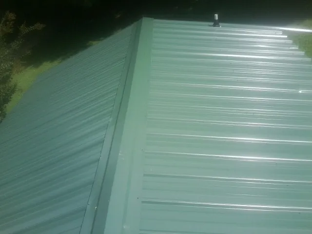 New green metal panels meeting at the ridge of a roof — Flat Roof Repair work by our crew in Valley Center