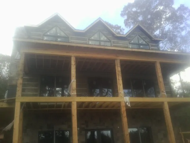 Dormers and porch framing on a large log home under construction — Roof Coating work by our crew in Valley Center