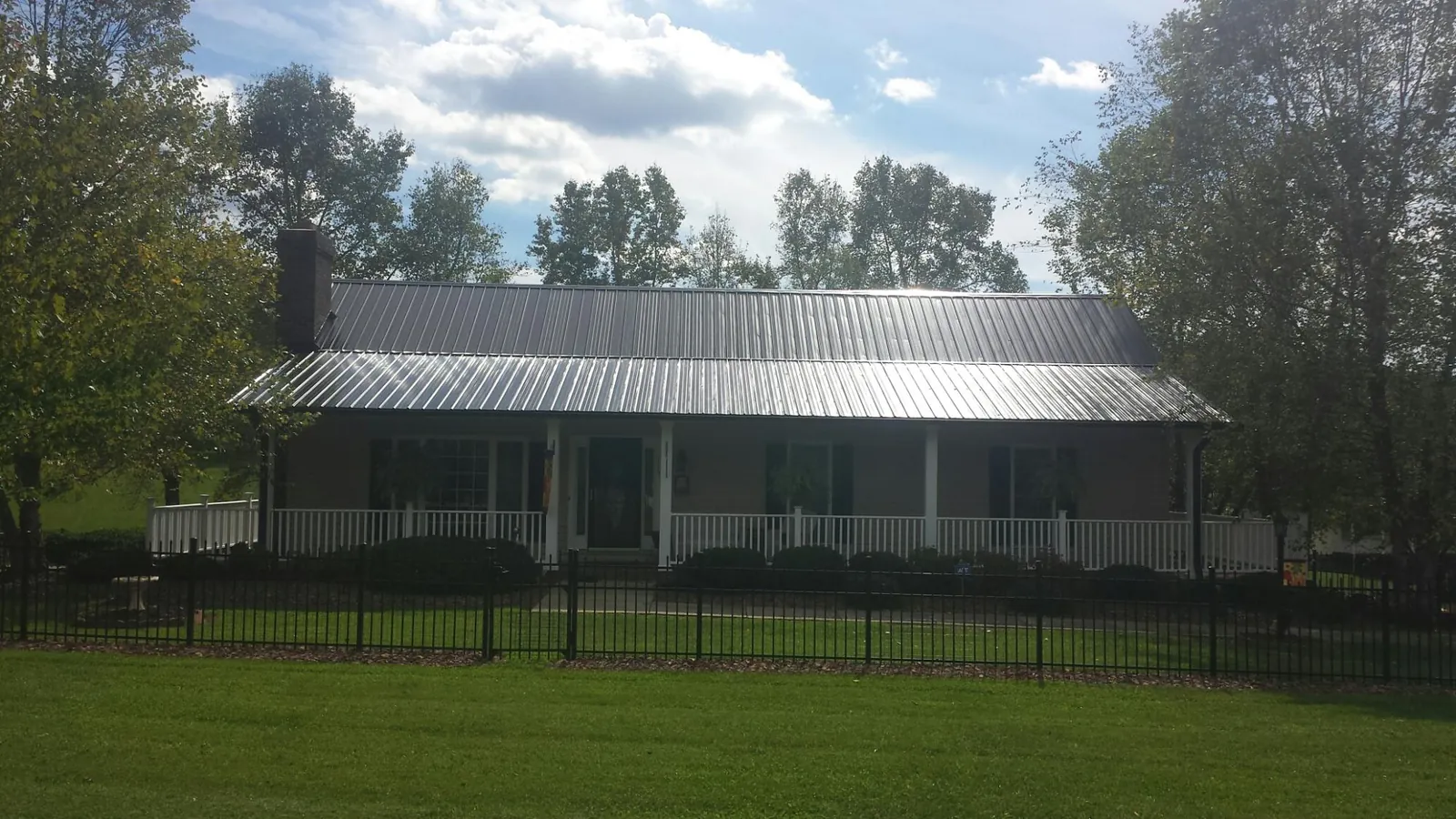Gray metal roof on a brick ranch with a full width front porch — Gutter Guard Installation work by our crew in Valley Center